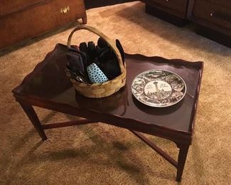 The same mahogany coffee table with scalloped edge, basket of eyeglasses and eyeglass cases and a San Antonio commemorative plate