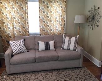 Grey modern sofa, decorative pillows, pole lamp, wall decor