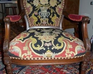 Exquisite Rococo style arm chair. Carved wood, oval back, needlepoint, crest enclosed panel. Demi cabriole front legs. Brass nail heads.
