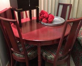 Red painted dining table with extra leaf and four chairs.