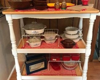 Rolling kitchen cart. Vintage Corningware - some pieces are new. Vintage wooden wooden salad set and salt and pepper grinder. Vintage Japanese enamelware. Other new serving pieces.