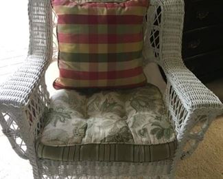 Large white wicker chair with magazine baskets on side