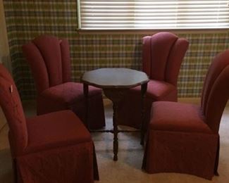 Four heart-shaped back upholstered chairs in a soft rose fabric, armless and skirted. Round cherry occasional table.