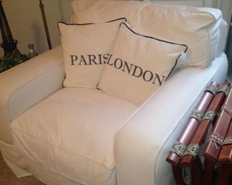A comfortable chair, Paris and London pillows, and luggage racks complete an inviting guest room!