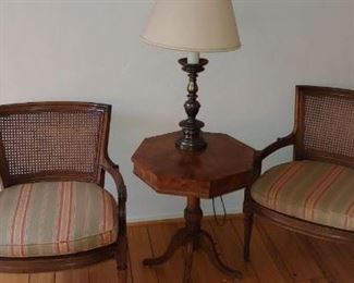 Two wicker cushioned arm chairs, end table and lamp