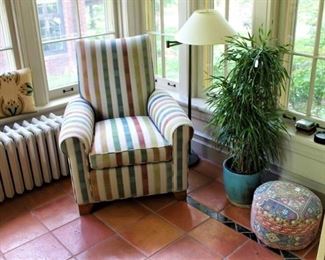 Custom upholstered chair shown with floor lamp and lovely home decor pieces.  