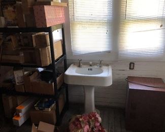 Back porch has lots of QVC new in box items, old pedestal sink, microwave.