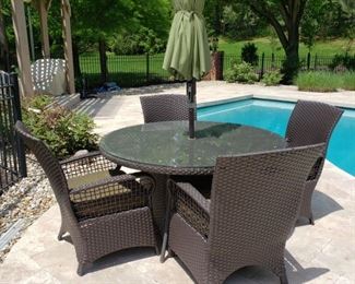 Round outdoor wicker patio table and four armchairs