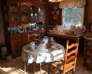 View of breakfast area of kitchen with large oak storage cabinet with lead glass doors.   Six oak ladder back chairs with rush seats