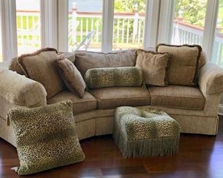 This is also a Wesley Hall curved sofa with pillows and shown with an animal print hassock and pillows.