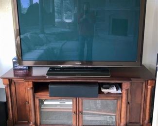 Big TV standing on a credenza. Looks like the shelf is tilted; my guess is that it wasn't put back on the right tier.  