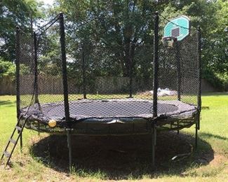 Double tiered trampoline bed with basketball goal and safety netting. 
