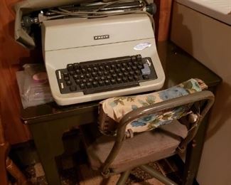 Electric typewriter with cover; metal typewriter table and chair.