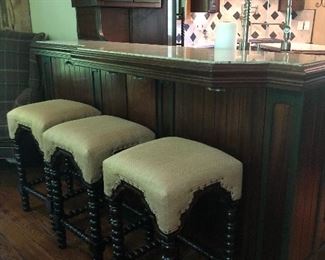 Three bar stools upholstered in cream-colored leather.  
