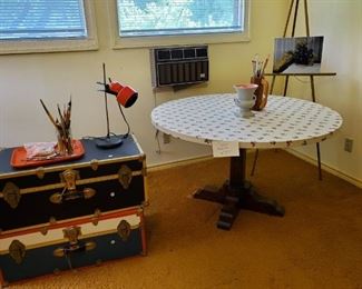 Craft table, camp boot trunks, paint brushes, task lighting