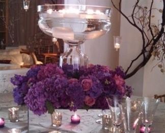 Mirror plinths, classic-shaped vessels in glass, hundreds of hanging glass candle holders, jewel-toned colored glass votives and oversized faux gems. 