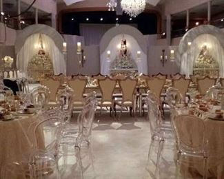 Decorative arch backgrounds in padded fabric with wood panel and mirror inserts. Acrylic and gold-trimmed chairs. Mirrored table tops. Crystal chandeliers. 