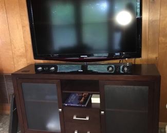 Samsung TV, sound bar and other electronic equipment, shown with contemporary entertainment cabinet.