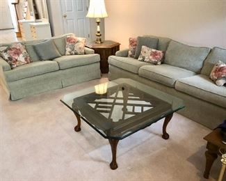 Sofa & loveseat in green upholstery & floral throw pillows.