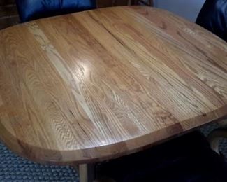 Very nice oak table with four real leather swivel chairs on casters. One leaf.