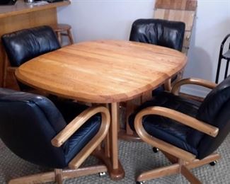 Very nice oak table with four real leather swivel chairs on casters. One leaf.
