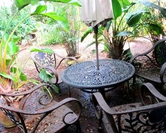 Patio furniture set with cast iron table and sun umbrella. Giant potted bird of paradise plants also looking for new loving home