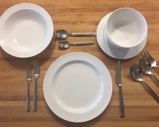 12 place settings of white stoneware; 12 place settings of 18/10 stainless flatware with serving pieces.