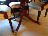 A view of the carved acanthus leaf saber legs and brass lion's paw cap feet of the BAKER table.  Casters are on the legs.