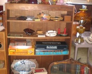 Bookshelf, antique beveled glass mirror with oak wood frame, cornucopia flower holders, pink fan, games, ash trays, amber glass shade lamp.