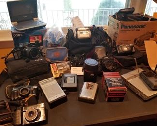 Packed Table of Vintage cameras, cassette players, DVD and Cd players/viewers, Video Cassette recorders, Miniature VHF/UHF Casio TV, Complete Kodak Easy Share Camera and Printer, etc