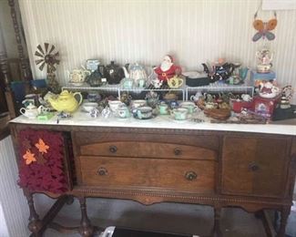 Antique buffet with collection of teapots and tea cups.