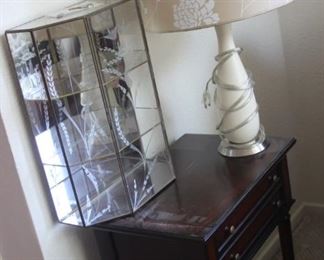 Two drawer end table, glass table top curio, table lamp.