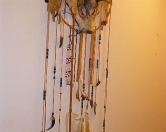 decorative wall hanging, complete with a wolf head, feathers, bone fish hook, claws & more