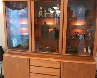 Lighted teak china cabinet with storage base including 4 pull out drawers.