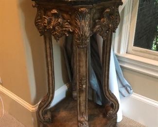 Elegant carved plant stand with marble top graced by a contemporary gold-toned bowl.