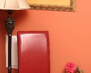 One of a pair of faux leather chairs next to  a low Chinese table.