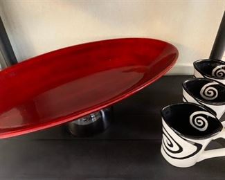 Swirly black/white cups and long red platter made of plastic.