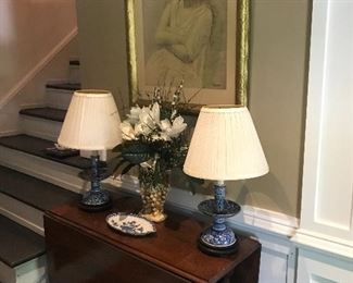 A drop leaf table in the foyer with a pair of older blue and white lamps and a wonderful early Picasso print