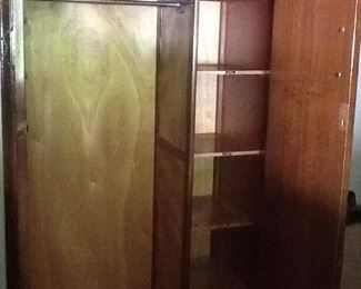 This is the inside of the wardrobe that consists of shelves on the right and a bar to hand things on the left.