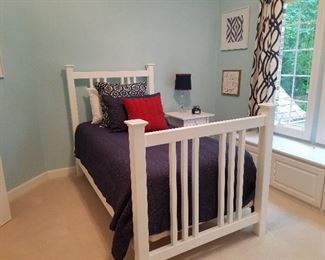 Twin bed with white, wooden, wide spindle headboard and foot board.