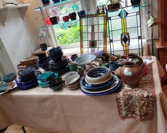 Table full of pottery and serving ware. Two sets retro dishware.