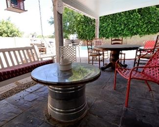 This is a round outdoor table with glass. Under the glass is a real wagon wheel. The base is metal.