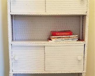 Over the toilet white wicker storage cabinet.