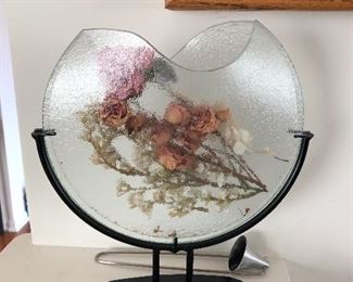 Half moon glass scupture vase with flowers inside on a metal base