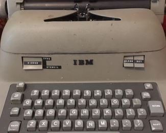 Electric typewriter by IBM with vinyl dust cover. Works but needs new ribbon.