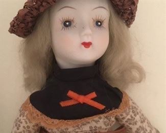 Antique bisque doll dressed in calico with painted eyes and shoes, cloth body