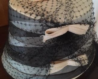 Tan hat with pink, black and gray wrapped ribbons and veil