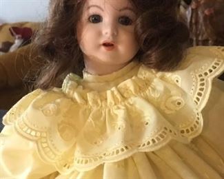 Antique brunette bisque doll dressed in yellow with glass eyes and open mouth, back of neck stamped 247 PARIS