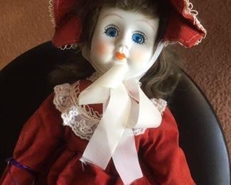 Antique bisque brunette doll dressed in red with glass eyes, painted lashes, cloth body and black leather boots