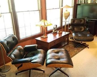 View in Den featuring a matching pair of Eames Lounge chairs (670) with ottomans (671).  Wood and leather in good condition.  Chairs estimated to be about 20 years old, per family. 